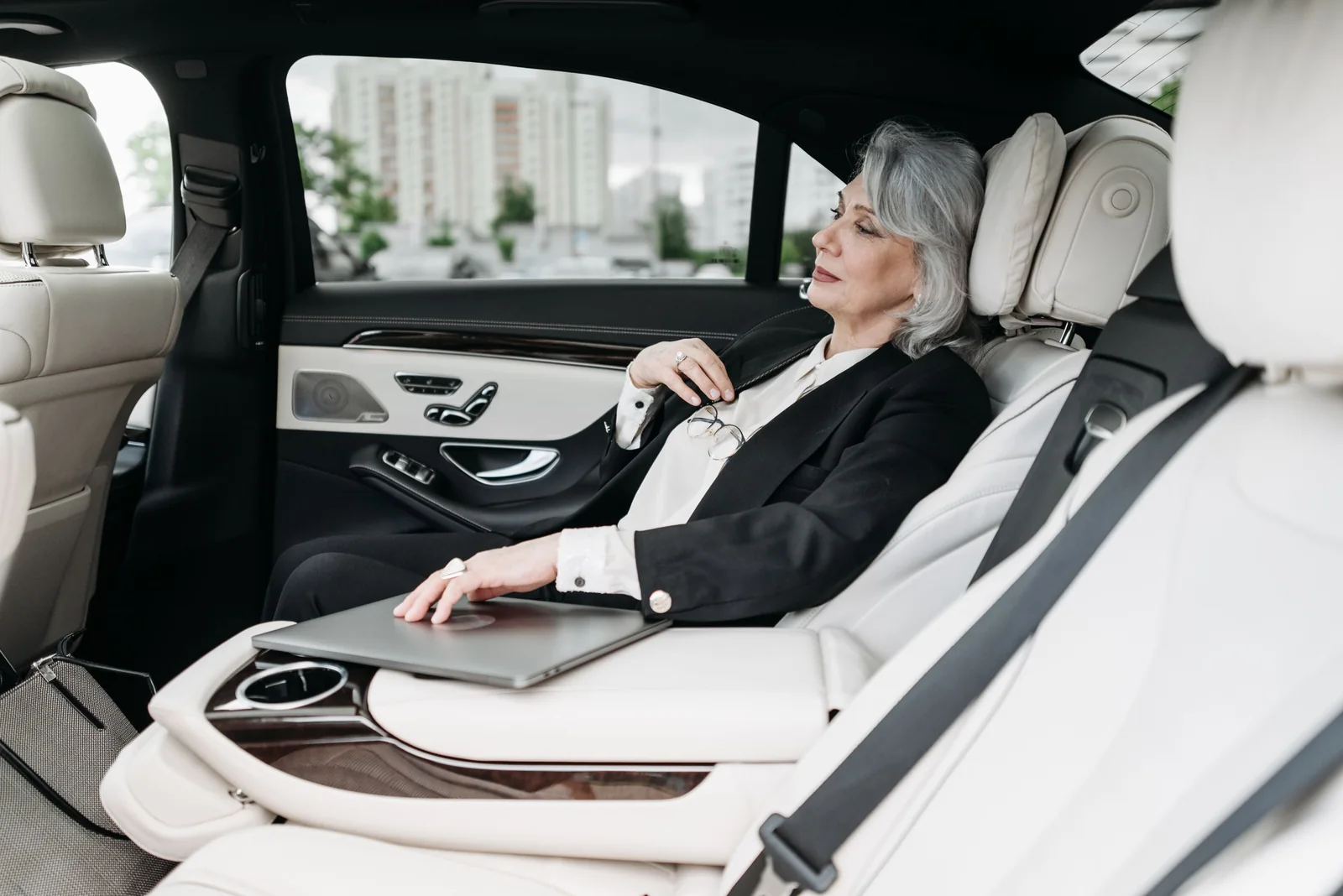 A passenger by the side window in a bright, white-leather back seat