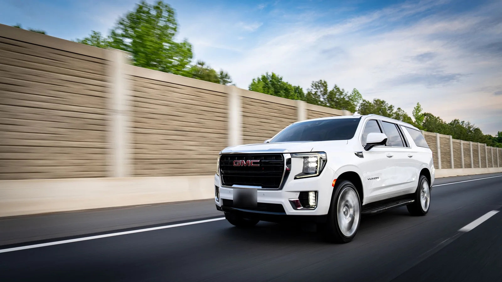 A white SUV with dark rear windows on a sunny highway