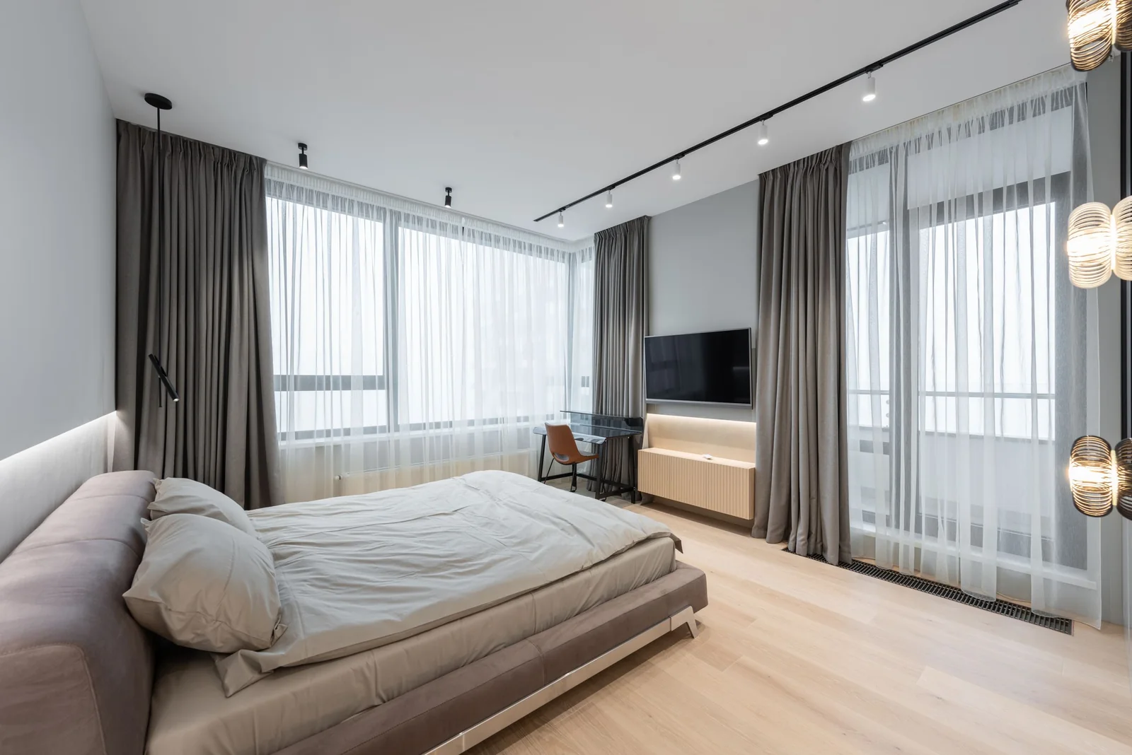 A bright bedroom with tall windows and sheer curtains