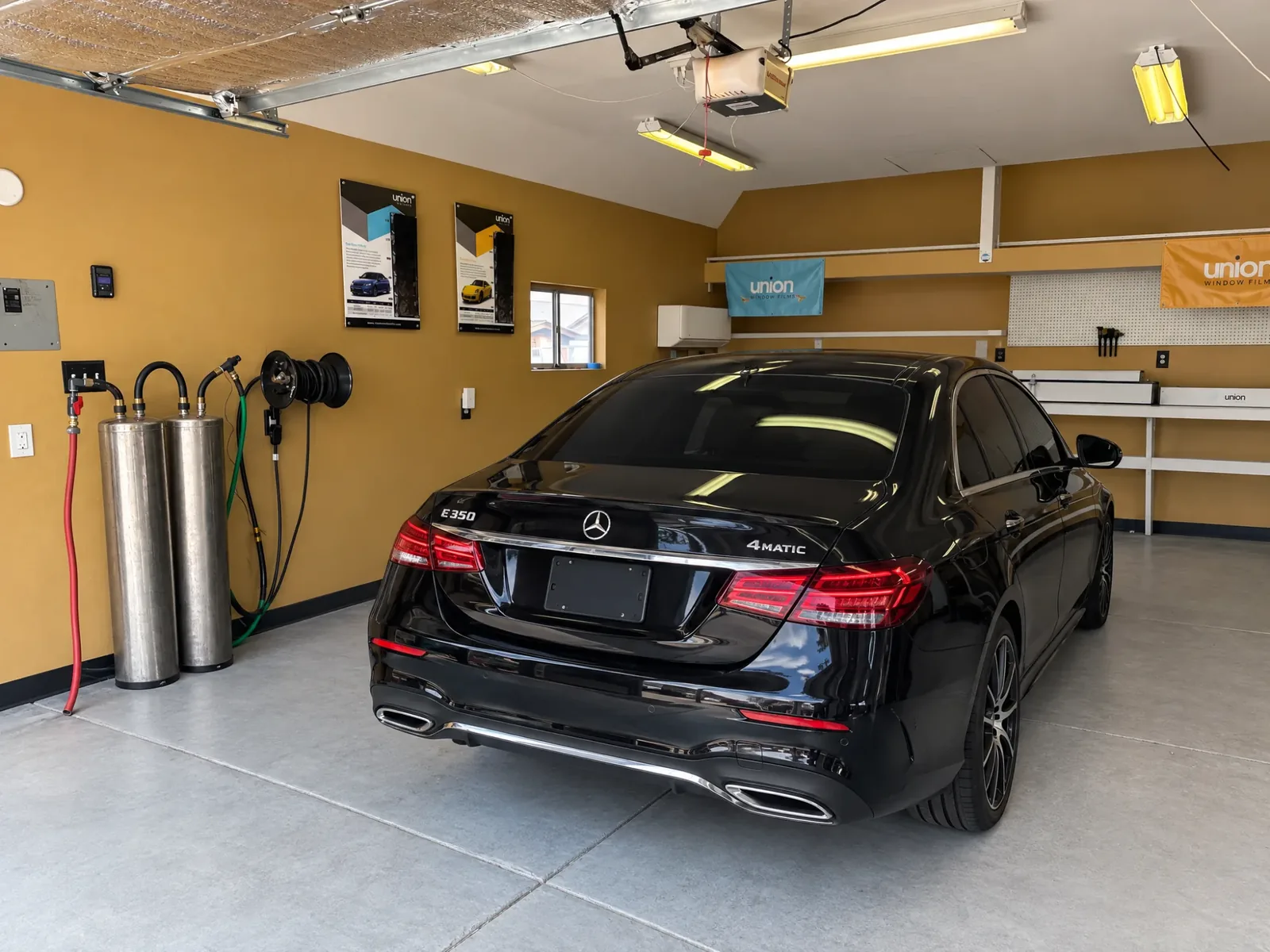 The Asap Window Tint bay from behind a tinted Mercedes, with the deionized water tanks on the left wall